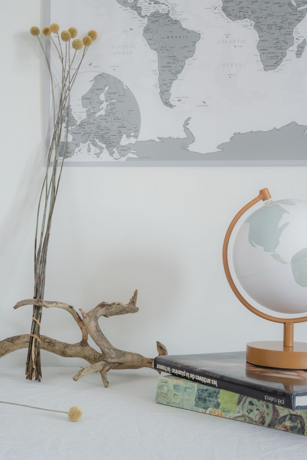 A small globe on a stand sitting on a stack of books in front of a world map.